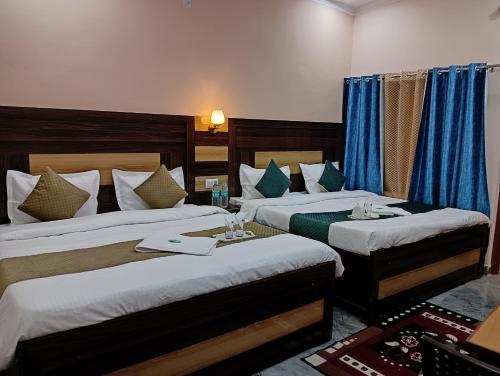 a hotel room with two beds and a table at Geetanjali Palace Hotel & Restaurant in Rudraprayāg