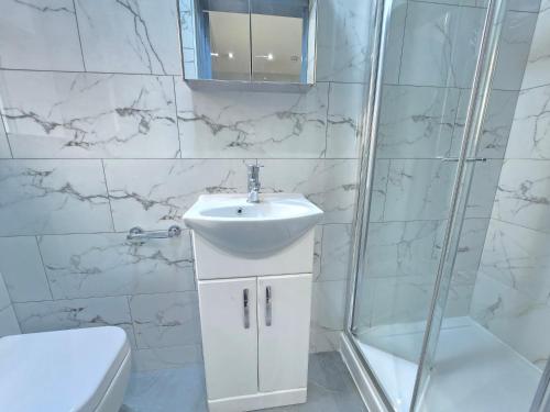 a white bathroom with a sink and a shower at Bedroom in shared house in Hounslow in Hounslow