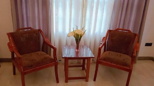 two chairs and a table with a vase of flowers on it at Moonplain Bungalows in Nuwara Eliya