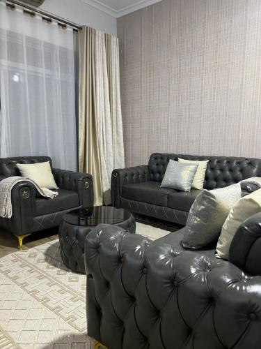 a living room with black leather couches and a couch at HA LUXURY 3BEDROOM LAKEVIEW munyonyo in Kampala
