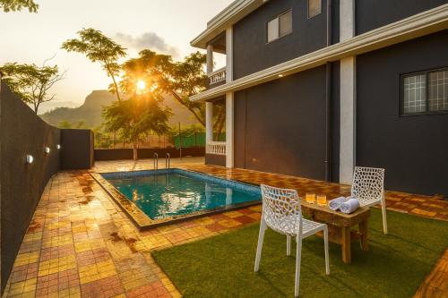 a backyard with a pool and two chairs and a table at EMPYREAN STAY 3BHK BLACK PANTHER VILLAll AC II PVT POOL II LUXURY ll in Lonavala