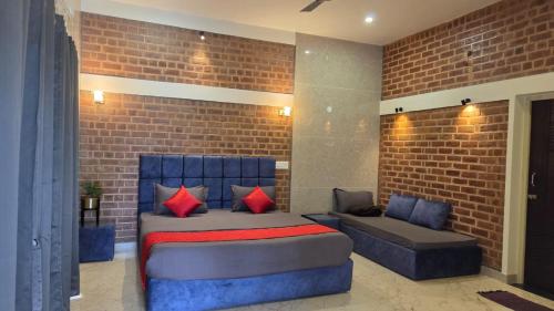 a bedroom with a bed and a couch and a brick wall at Athulya Resort -Leisure and Luxury cottages from EMBEHolidays in Kottaikadu