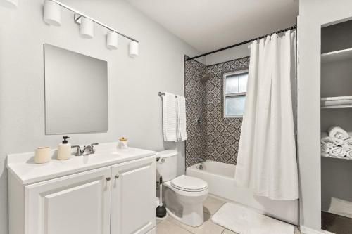 a white bathroom with a toilet and a sink at Spacious Retreat with Pool & Hot Tub - 10 Minutes to Downtown in San Antonio