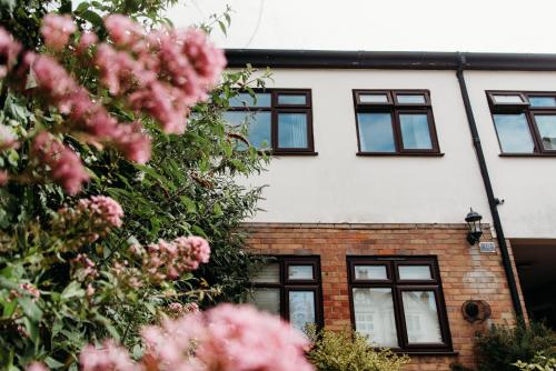 una casa con ventanas negras y flores rosas en Shoebury Lodge near Sea front In Southend, en Southend-on-Sea