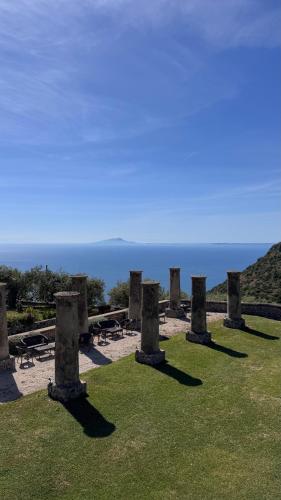 a group of stone pillars in a field with the ocean at Relais Villa Giusso in Vico Equense