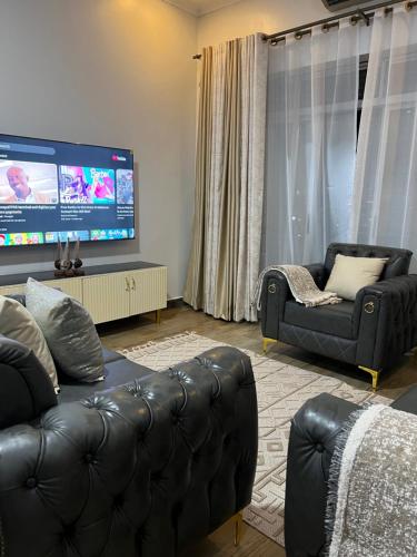 a living room with a black leather couch and a flat screen tv at HA LUXURY 3BEDROOM LAKEVIEW HOME munyonyo in Kampala