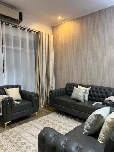 a living room with two black couches and a couch at HA LUXURY 3BEDROOM LAKEVIEW HOME munyonyo in Kampala
