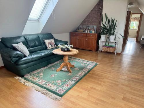 a living room with a black leather couch and a table at Charmigt hus på landet in Höör