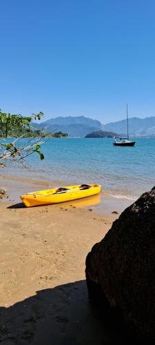 een gele kajak op een strand met een boot in het water bij Veleiro Alpha 22 Privativo in Paraty