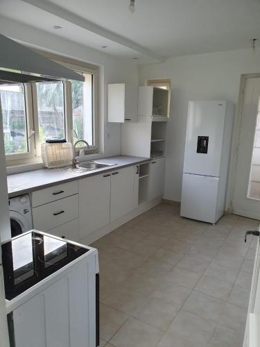 a kitchen with white cabinets and a white refrigerator at appartement avec beau jardin in Blois