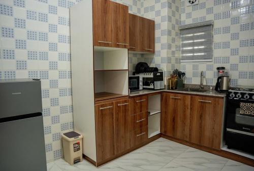 a small kitchen with wooden cabinets and a stove at Austin's Apartment in Port Harcourt