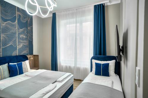 two beds in a room with blue curtains and a window at Odeon Designer Apartments and Rooms I Self Check In in Vienna