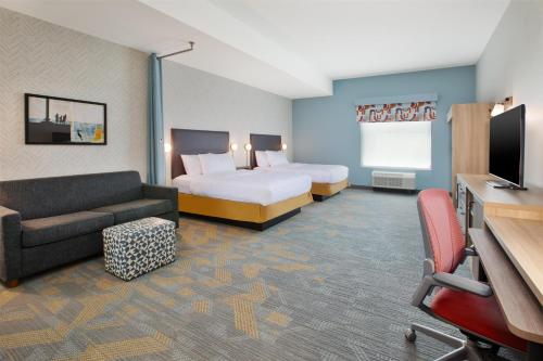 a hotel room with two beds and a couch at Home2 Suites By Hilton Traverse City in Traverse City