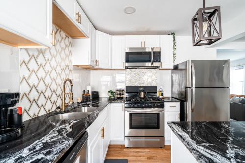 a kitchen with white cabinets and stainless steel appliances at East Side Spa Retreat Near Lake in Milwaukee