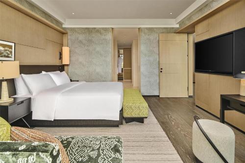 a hotel room with a bed and a flat screen tv at Shu Hua Hotel Tianmu Mountain, Curio Collection By Hilton in Hangzhou