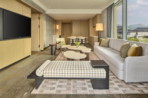 a living room with a couch and a tv at Shu Hua Hotel Tianmu Mountain, Curio Collection By Hilton in Hangzhou