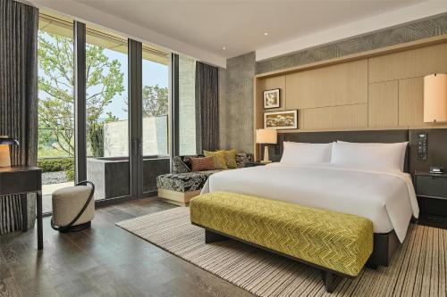 a bedroom with a large bed and a living room at Shu Hua Hotel Tianmu Mountain, Curio Collection By Hilton in Hangzhou