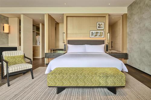 a bedroom with a large bed and a chair at Shu Hua Hotel Tianmu Mountain, Curio Collection By Hilton in Hangzhou