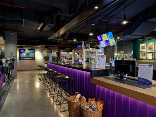 a bar in a restaurant with purple walls and stools at Tru by Hilton Hanoi Station in Hanoi