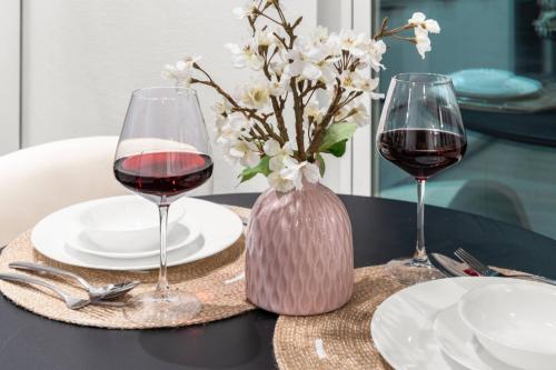 a table with two glasses of wine and a vase of flowers at Japandi Style 1BR Escape w EV Charger, Bishop Arts in Oak Cliff