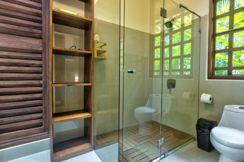 a bathroom with a toilet and a glass shower at Casa Xcanan Pool House in Punta Uva