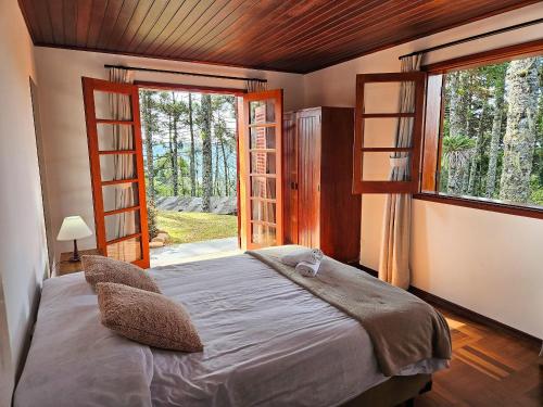 a bedroom with a bed and a large window at Refúgio das Nuvens | by The Lodges in Campos do Jordão