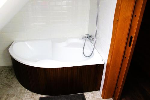 a bath tub in a bathroom with a shower at H25 Vendégház in Sóskút
