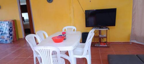 a white table with white chairs and a television at Quinta AM Vacaciones y Turismo in Santa Isabel