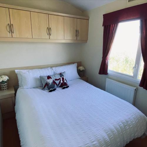 a bedroom with a white bed with two stuffed animals on it at Golden palm 7 berth holiday home in Chapel Saint Leonards