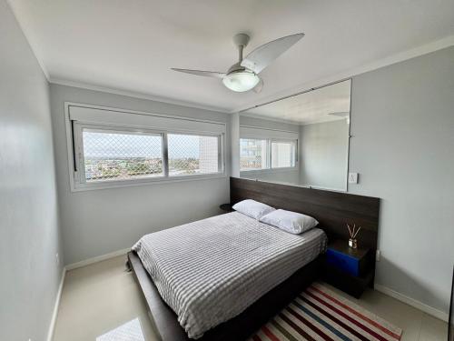 una camera con letto, ventilatore a soffitto e specchio di Apto alto padrão na Praia de Torres - 550m do mar a Torres