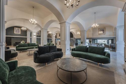 a living room with green couches and a table at Gran Hotel Panamericana, Mérida in Mérida