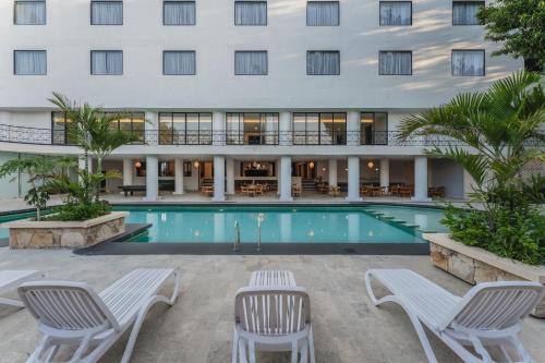 a hotel with a pool and chairs and a building at Gran Hotel Panamericana, Mérida in Mérida