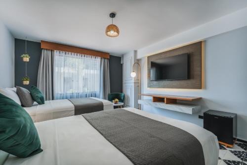 a hotel room with two beds and a flat screen tv at Gran Hotel Panamericana, Mérida in Mérida