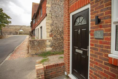 a brick building with a black door on a street at The Old Coach House -Pevensey in Pevensey