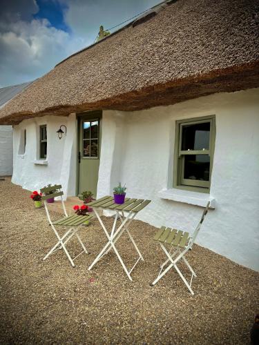 two chairs and a table in front of a cottage at Murphys Thatched Cottage in Mitchelstown