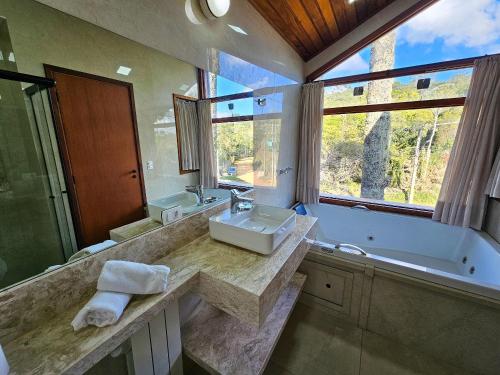 a bathroom with a sink and a bath tub and a window at Refúgio das Nuvens | by The Lodges in Campos do Jordão