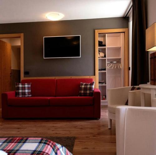 a living room with a red couch and a tv at Ciasa Alpina Relax Hotel in Moena
