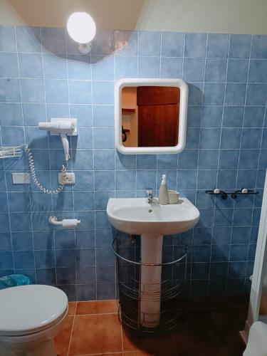 a blue tiled bathroom with a sink and a toilet at appartamento Colticciola Agriturismo Marche in Cagli