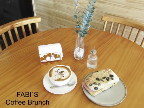 a table with a cup of coffee and a pastry on it at Dein Haus Hotel y Departamentos in Puerto Varas
