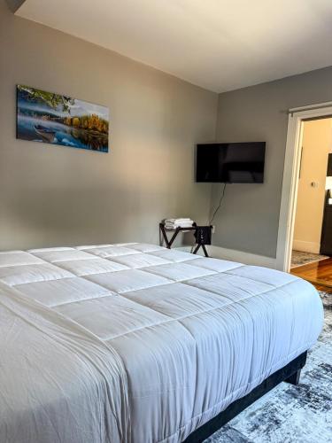 a bedroom with a white bed and a flat screen tv at Stylish Stay By Beach And Shops in Beverly