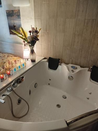 un baño con bañera y un jarrón de flores en Ramgon, en Gonio