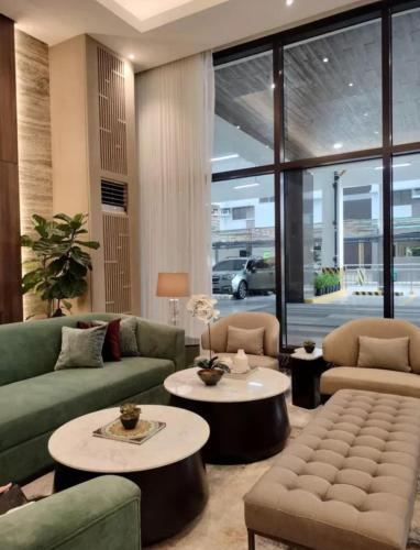 a living room with couches and tables and a large window at Aurora Escalades Residences in Manila