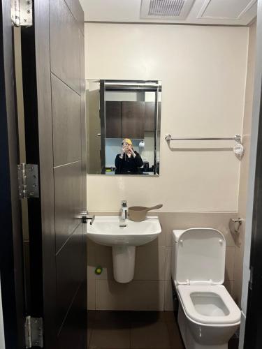 a person taking a picture of a bathroom with a toilet and sink at Aurora Escalades Residences in Manila