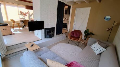 a living room with a couch and a tv at Vakantiehuis Lycka in Noordwijkerhout