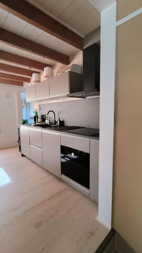 a kitchen with white cabinets and a black stove at Vakantiehuis Lycka in Noordwijkerhout