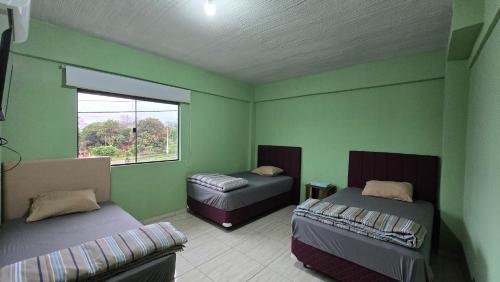 a green room with two beds and a window at Rd hotel in Colonia Felicidad