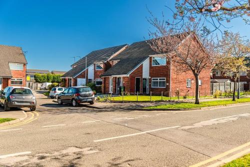 a house with cars parked on the side of the street at 2 Bedroom Apartment Denton, suitable for professionals needing a peaceful work environment in Manchester