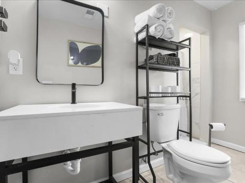 a bathroom with a toilet and a sink and a mirror at Chic Vinewood Home King Plus 2 Queens in Detroit