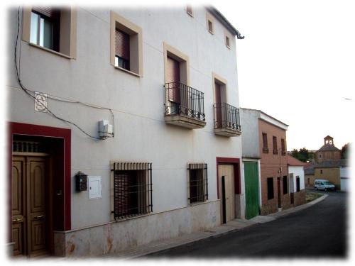 - un bâtiment blanc avec balcon sur le côté d'une rue dans l'établissement Centro Ornitológico El Primillar, à Cañada de Calatrava