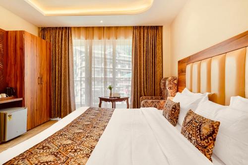 a hotel room with a bed and a window at Hotel Classic Hills Bhagsunag Luxury Stay #Best Hotel in Mcleodganj #Mountain View Balcony Rooms #Spacious Parking #Prime Location in Dharamshala #Near Bhagsunag Waterfall #Top Selling Property in Mcleodganj in Dharmsala